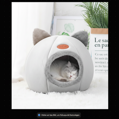 Weiße Katze schläft friedlich in grauer Katzenhöhle mit Katzenohren